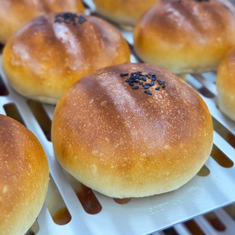 Glossy red bean buns cooling on a tray